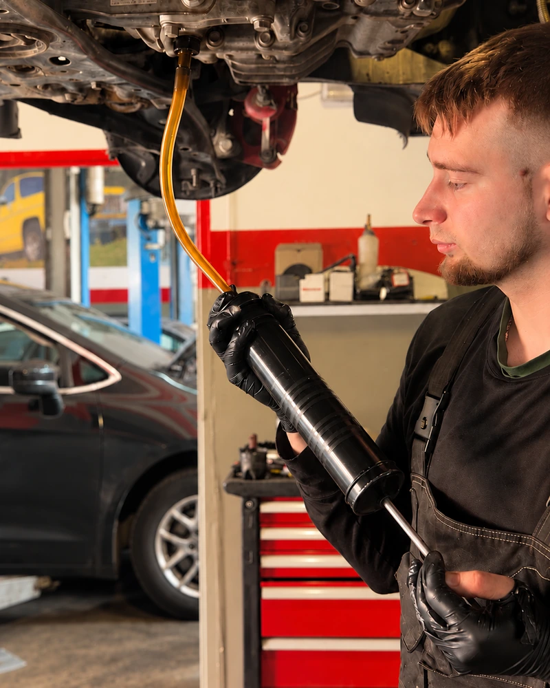 Mechanik pracujący przy samochodzie uniesionym na podnośniku.